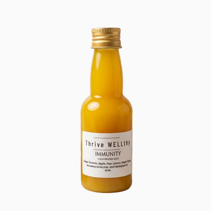 Bottle of 'Thrive Wellery' immunity juice with fruits and honey on a marble surface